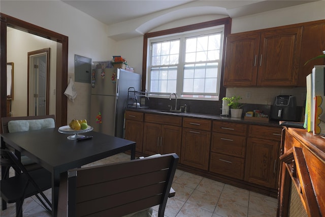 kitchen featuring stainless steel refrigerator, light tile patterned floors, sink, and backsplash