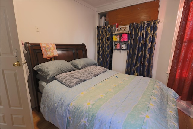 bedroom with hardwood / wood-style flooring, crown molding, and a closet