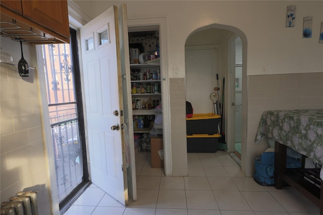 interior space with tile patterned floors, radiator heating unit, and tile walls