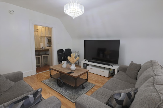 living room featuring lofted ceiling, a notable chandelier, and hardwood / wood-style flooring