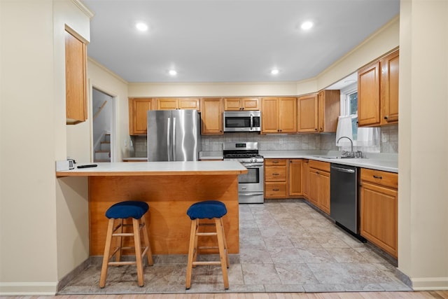 kitchen featuring appliances with stainless steel finishes, a breakfast bar, sink, decorative backsplash, and kitchen peninsula