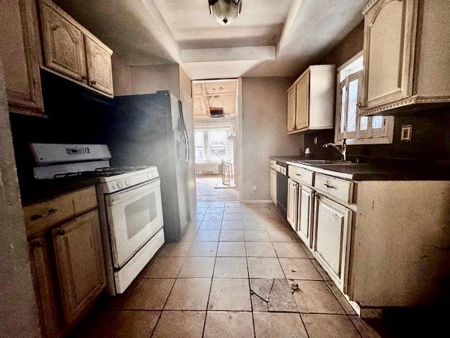 kitchen featuring light tile patterned flooring, dishwasher, sink, white range with gas stovetop, and a tray ceiling