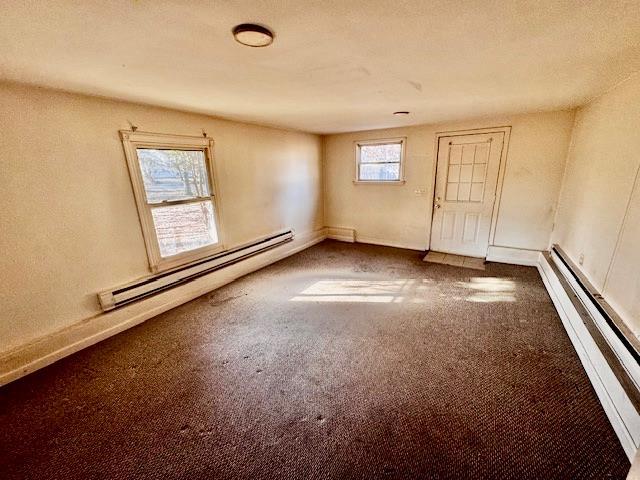 carpeted spare room featuring a baseboard radiator