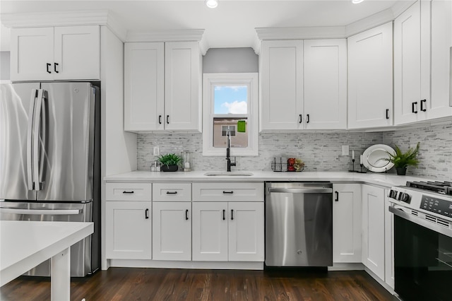 kitchen with sink, appliances with stainless steel finishes, dark hardwood / wood-style floors, white cabinets, and decorative backsplash