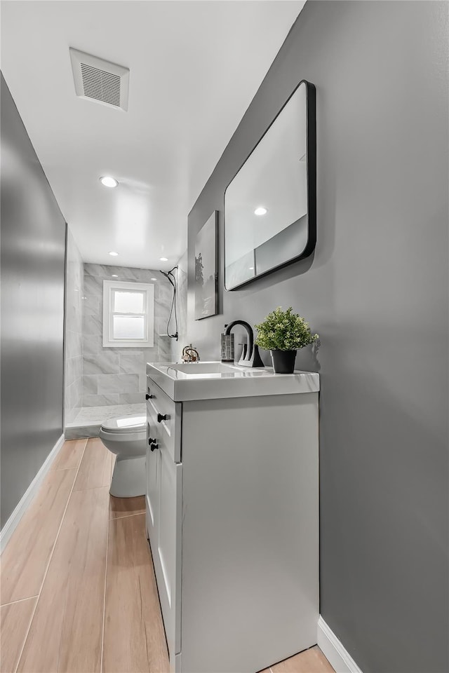 bathroom featuring vanity, tiled shower, and toilet