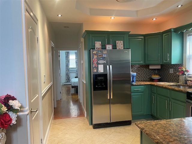 kitchen with green cabinetry, a tray ceiling, stainless steel fridge with ice dispenser, and light tile patterned floors