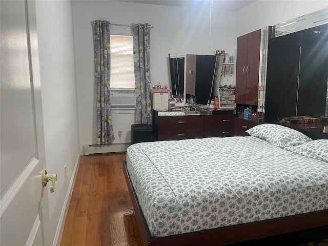 bedroom with a baseboard heating unit and hardwood / wood-style flooring