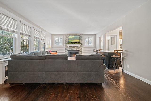 living room with dark wood-type flooring and a stone fireplace