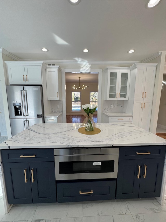 kitchen with ornamental molding, high end fridge, and white cabinets