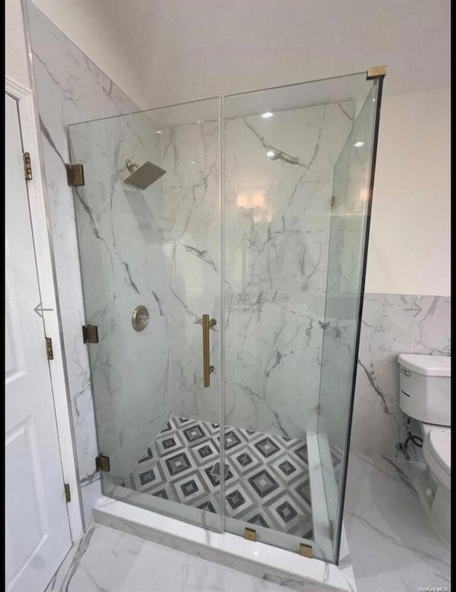 bathroom with toilet, tile walls, and a shower with shower door