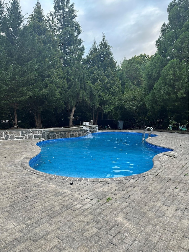 view of swimming pool featuring pool water feature and a patio