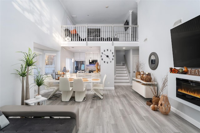 dining space featuring crown molding, light wood-type flooring, and a high ceiling