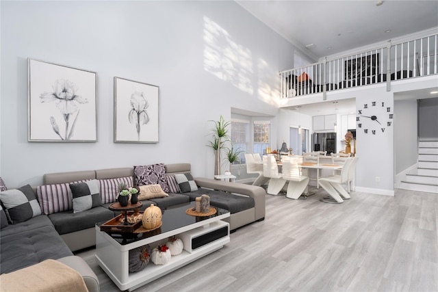 living room featuring crown molding, light hardwood / wood-style floors, and a high ceiling