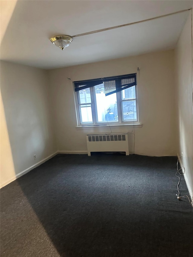 carpeted empty room featuring radiator heating unit