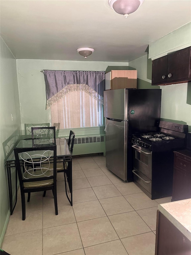 kitchen with dark brown cabinetry, radiator, light tile patterned floors, and appliances with stainless steel finishes