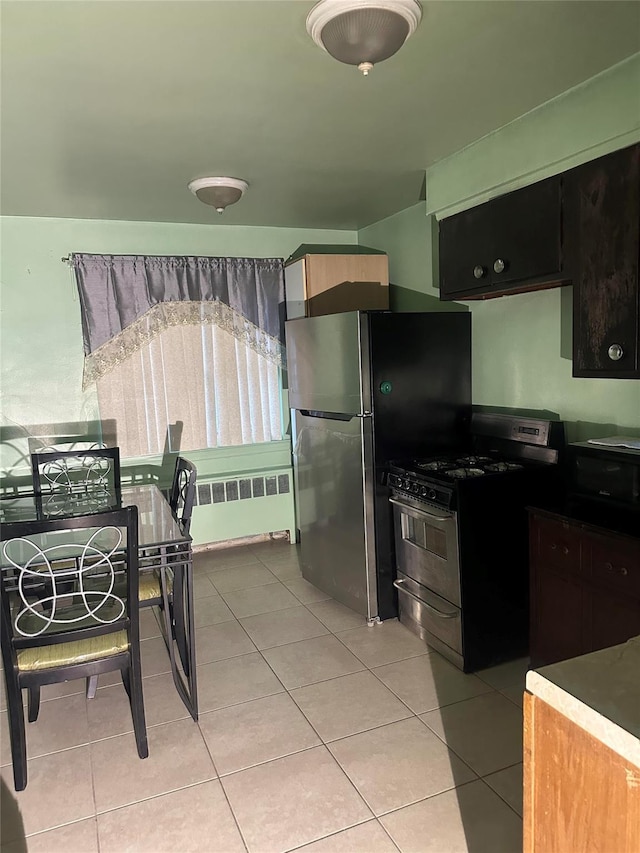 kitchen featuring appliances with stainless steel finishes, radiator heating unit, and light tile patterned floors