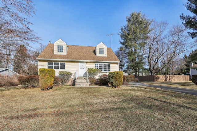 cape cod-style house with roof with shingles, fence, and a front lawn