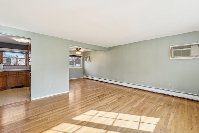 interior space featuring baseboards, a ceiling fan, light wood-style flooring, a wall mounted air conditioner, and baseboard heating