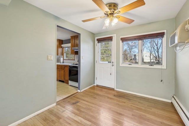 interior space featuring baseboards, ceiling fan, light wood finished floors, and baseboard heating