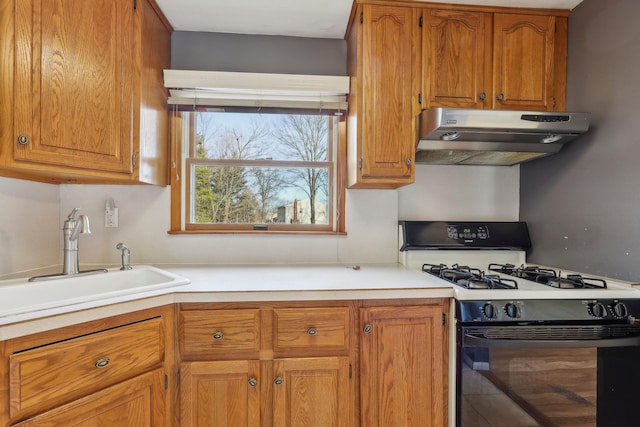 kitchen with range with gas stovetop, brown cabinets, light countertops, under cabinet range hood, and a sink