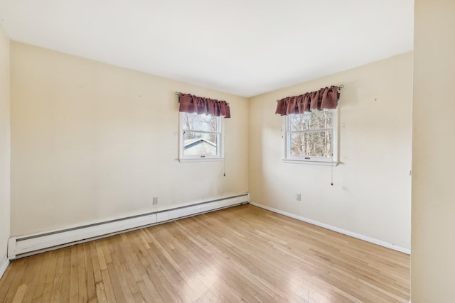 unfurnished room featuring baseboard heating, wood-type flooring, and baseboards