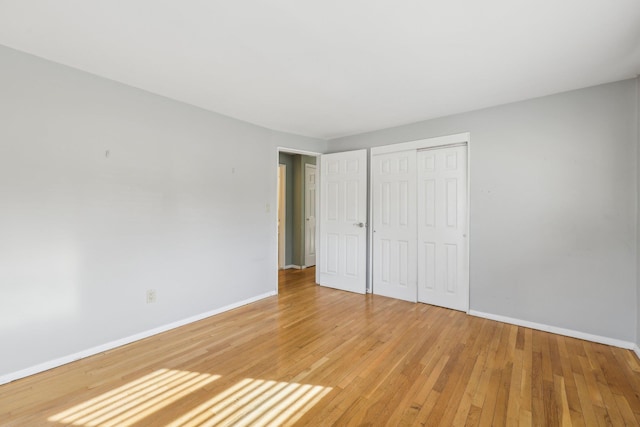 unfurnished bedroom featuring a closet, baseboards, and light wood finished floors