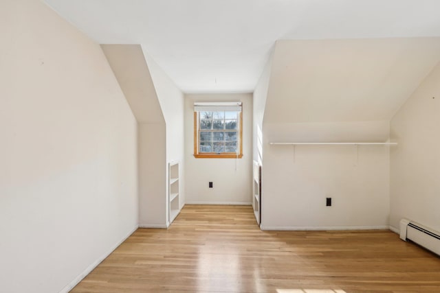 additional living space with light wood-style flooring and baseboard heating