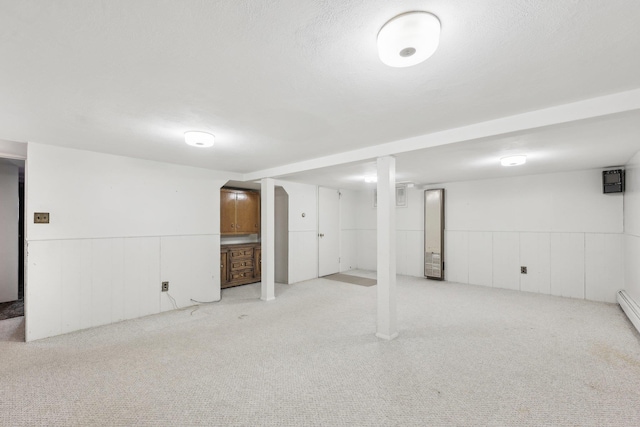 finished below grade area featuring a wainscoted wall, carpet, and a textured ceiling