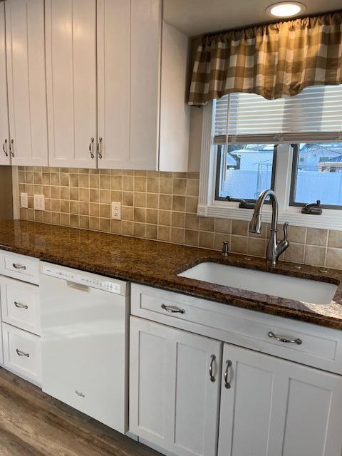 kitchen featuring sink, white cabinets, white dishwasher, and dark stone counters