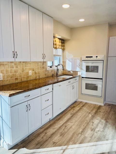 kitchen with white cabinetry, sink, white appliances, and light hardwood / wood-style flooring