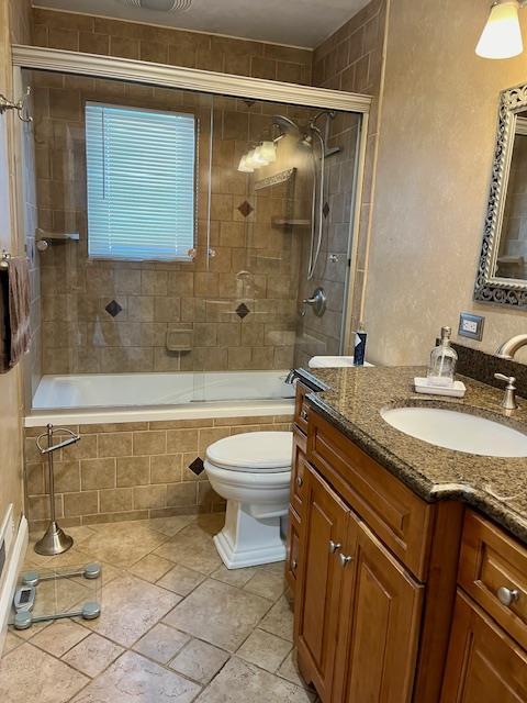 full bathroom featuring vanity, enclosed tub / shower combo, and toilet