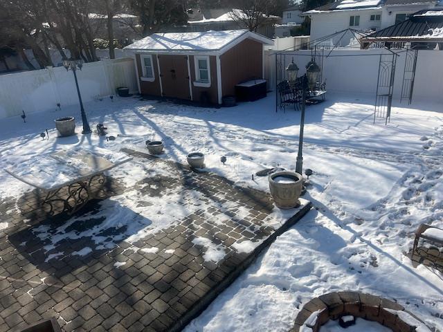 yard covered in snow with a fire pit and a storage unit