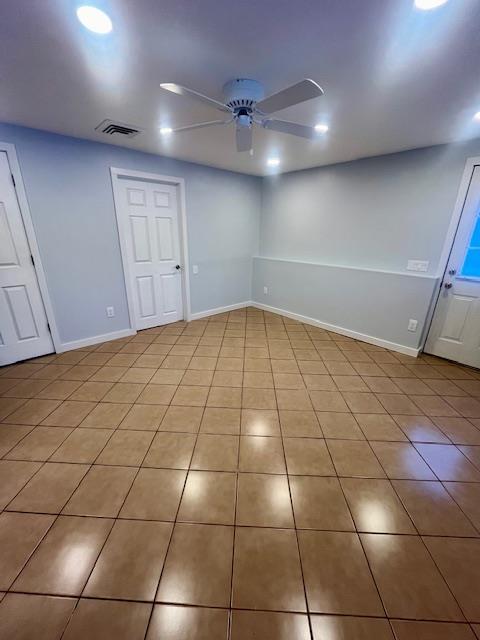 tiled spare room with ceiling fan