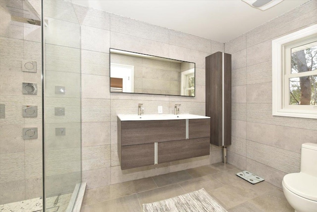 bathroom with tile walls, tile patterned flooring, vanity, a tile shower, and toilet