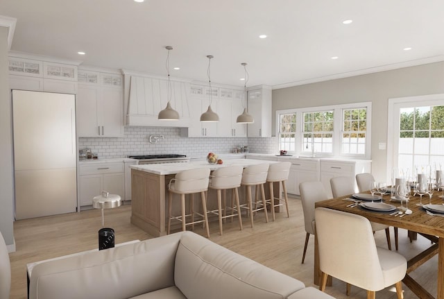 kitchen with pendant lighting, white cabinetry, a center island, light stone countertops, and decorative backsplash