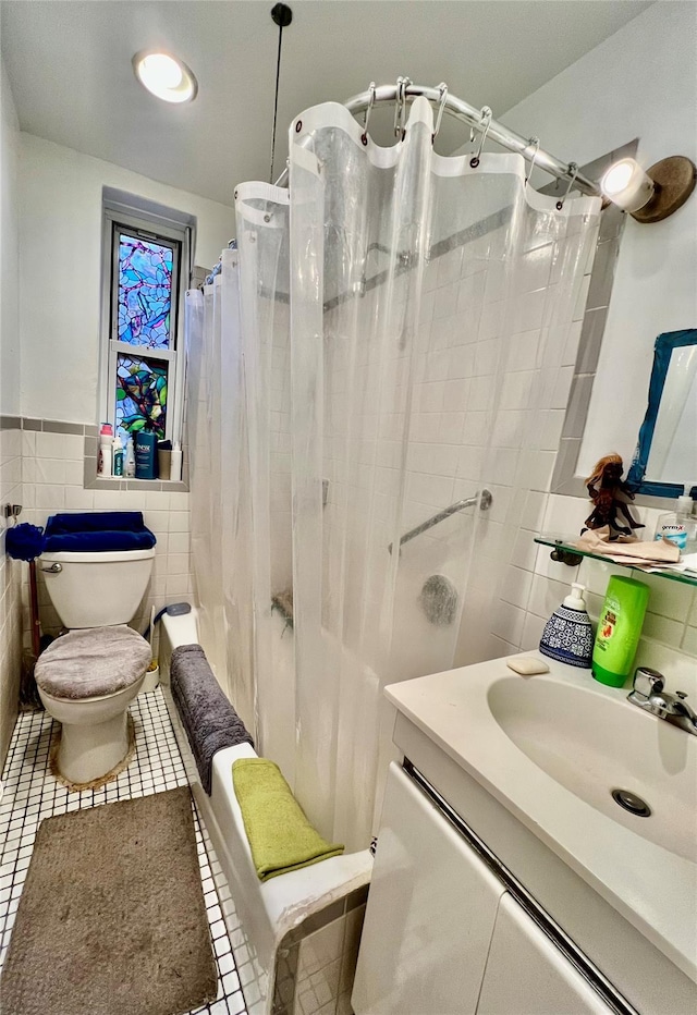 bathroom featuring vanity, toilet, tile patterned flooring, and tile walls