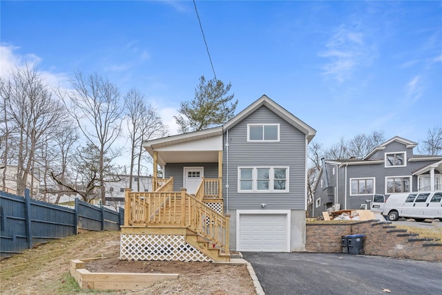 view of front of property with aphalt driveway, a porch, a garage, and fence