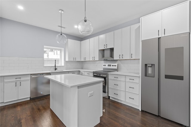 kitchen featuring tasteful backsplash, stainless steel appliances, wall chimney range hood, and a sink