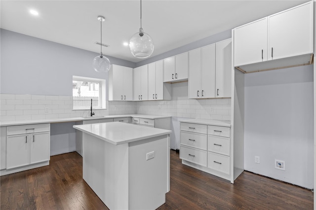 kitchen with tasteful backsplash, dark wood finished floors, a kitchen island, and a sink