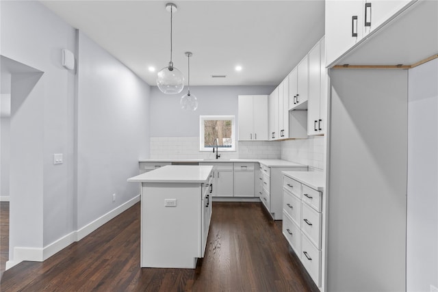 kitchen with tasteful backsplash, a center island, dark wood-type flooring, and a sink