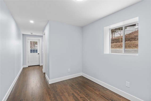 hallway featuring dark wood finished floors and baseboards