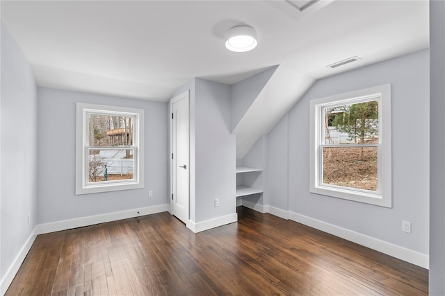 bonus room featuring visible vents, dark wood-type flooring, baseboards, and vaulted ceiling