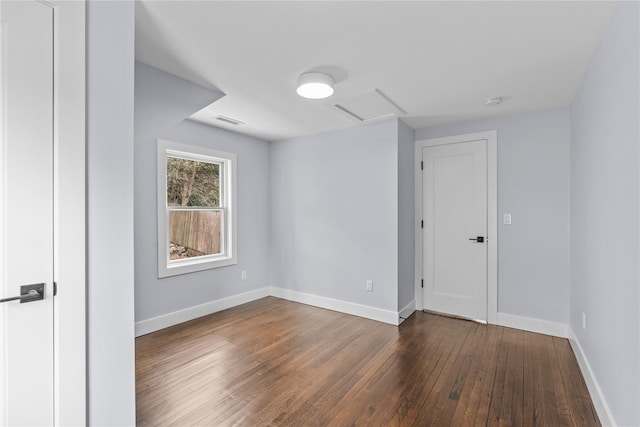 unfurnished room featuring visible vents, attic access, baseboards, and wood-type flooring