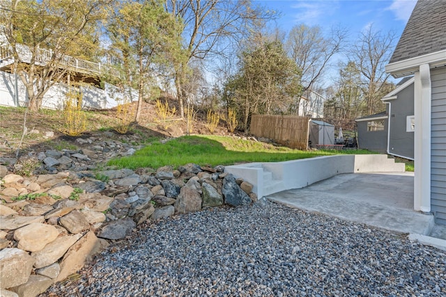 view of yard featuring an outdoor structure, a patio area, a shed, and fence