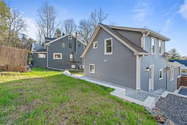 back of property featuring fence, roof with shingles, and a yard