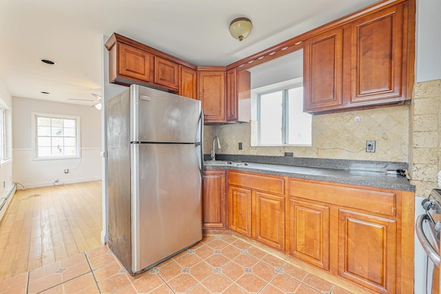 kitchen featuring sink, backsplash, stainless steel fridge, and light tile patterned floors