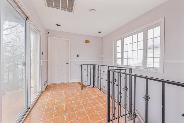 hallway with a baseboard heating unit and light tile patterned floors