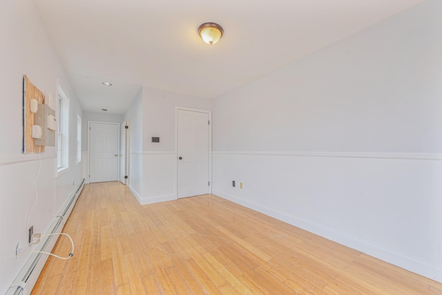 spare room featuring a baseboard heating unit and light wood-type flooring