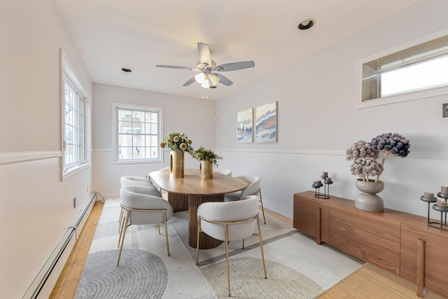 dining space with a baseboard heating unit, light hardwood / wood-style flooring, and ceiling fan