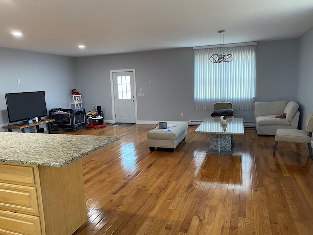 living room featuring baseboard heating, a baseboard heating unit, baseboards, and hardwood / wood-style flooring